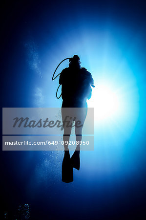 Silhouetted man scuba diving in ocean, Bali, Indonesia