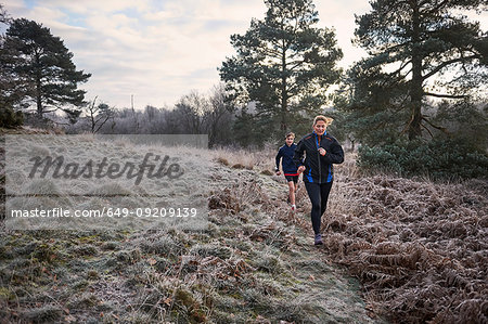 Front view of mother and son running on frosty grassland