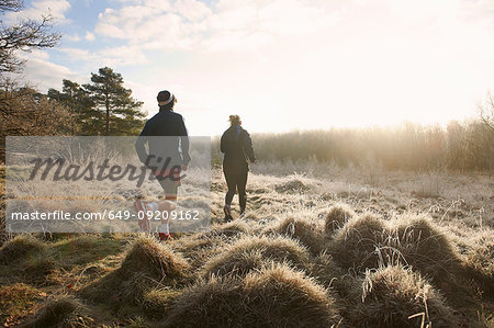 Rear view of mother and son running on grassland