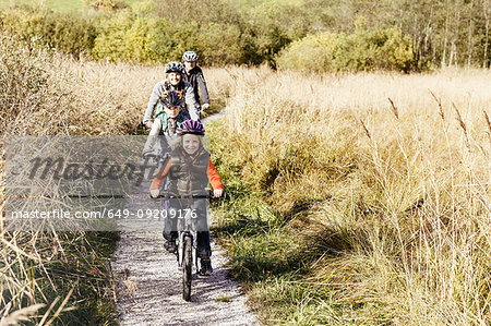 Front view of family cycling on rural path looking at camera smiling