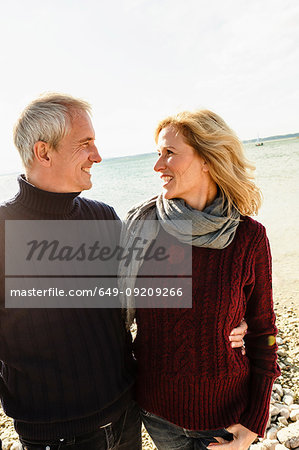 Mature couple beside lake, face to face, smiling