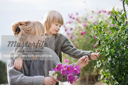 Boy and mother tending flowers in organic garden