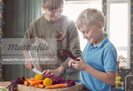 Mother and son preparing organic vegetables in kitchen