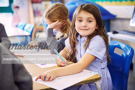 Portrait of girl drawing at desk in elementary school