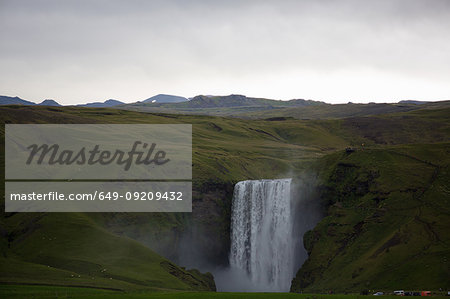 Waterfall flowing from lush green cliffs, Iceland
