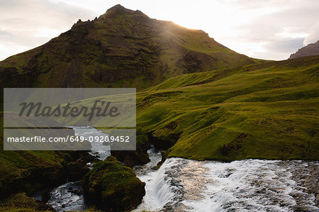 River flowing by lush green mountain range, Iceland