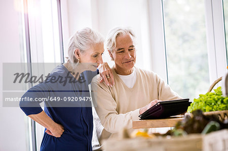 Senior couple browsing digital tablet recipes at kitchen counter