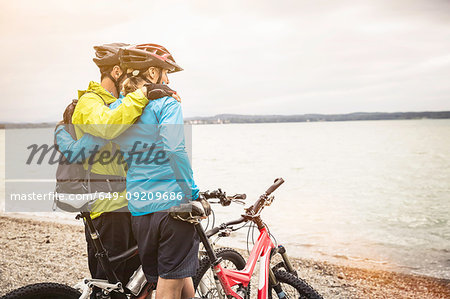 Romantic mountain biking couple looking out from lakeside
