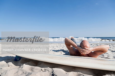 Surfer lying on surfboard on beach