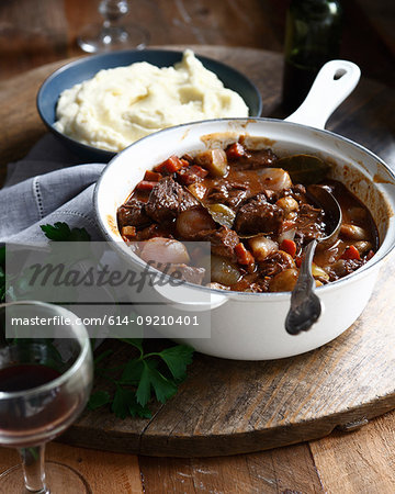 Beef daube in casserole dish with bowl of mashed potatoes