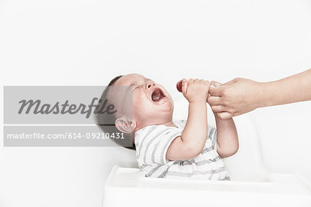 Hand taking lollipop from crying baby