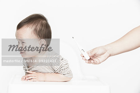 Baby boy crying, hand holding digital thermometer