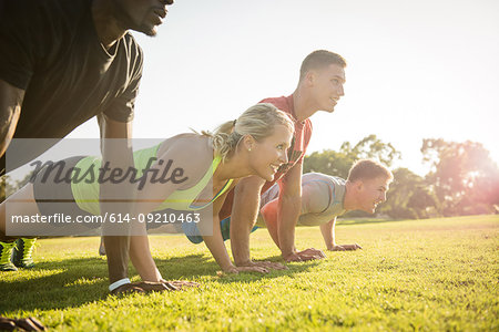 Group of young adults doing push-ups in field