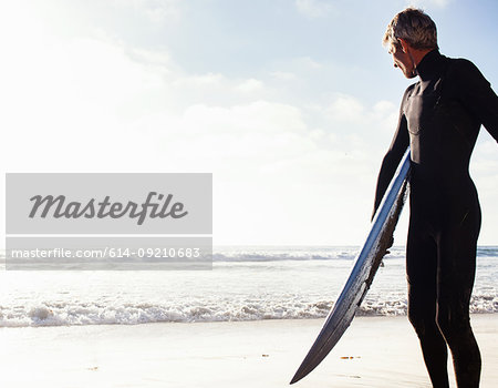 Man at coast with surfboard, Encinitas, California, USA