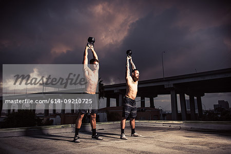 Two men training with kettlebells on gymnasium rooftop