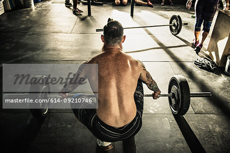 Mid adult man preparing to lift barbell in gymnasium