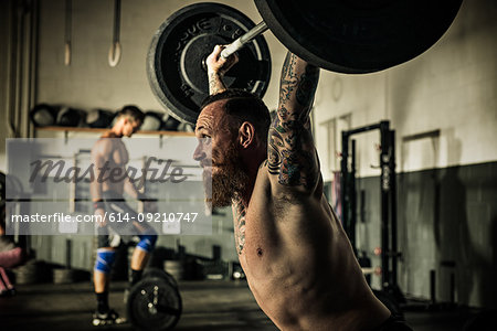 Mid adult man lifting barbell in gymnasium