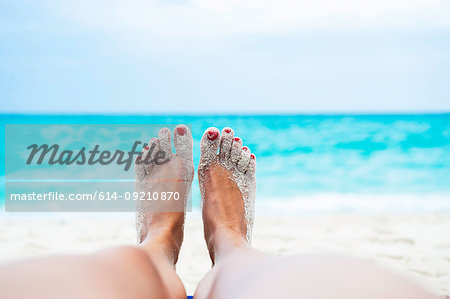 Close up of female legs and feet sunbathing on beach