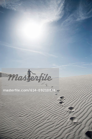 Young man walking across sand dune, White sands, New Mexico,  USA