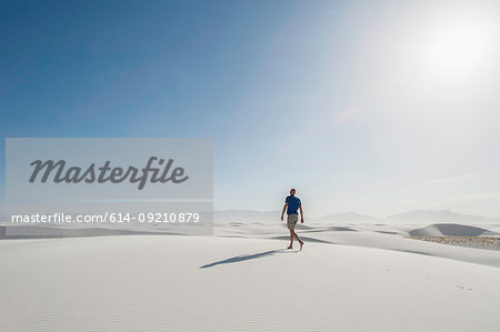 Young man walking on sand dune, White sands, New Mexico,  USA
