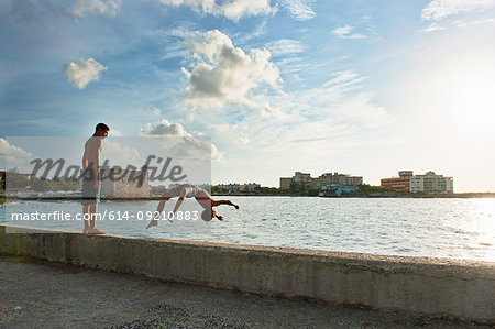 Two boys playing and diving from harbor wall, Havana, Cuba