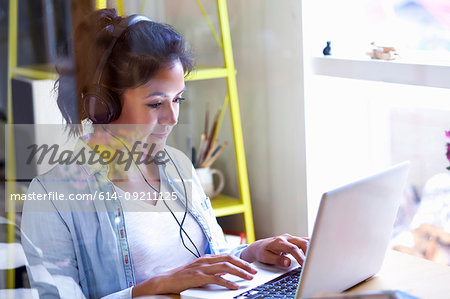 Young woman with headphones using laptop