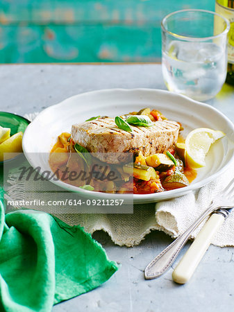 Still life plate of tuna, bean and tomato stew with lemon garnish