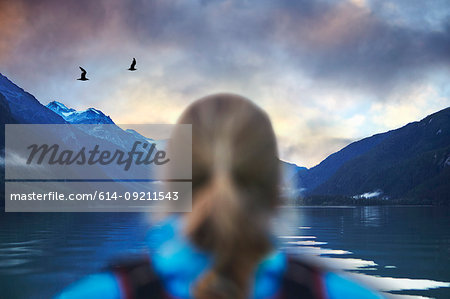 Rear view of female hiker gazing at seagulls and mountain lake, Haines, Alaska, USA
