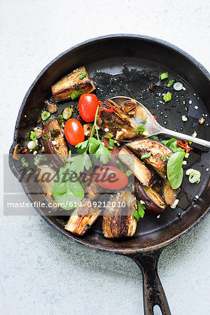 Still life of fried aubergines with plum tomatoes in frying pan