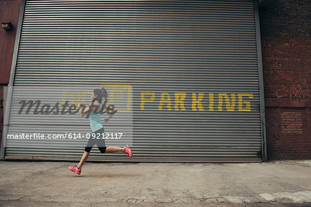 Young female runner running on city street