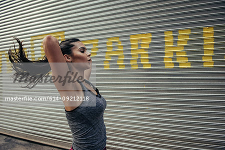 Young female runner tying up ponytail