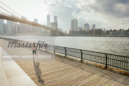 Young female runner running along riverside, Brooklyn, New York, USA
