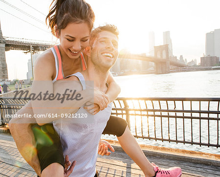 Young male runner piggybacking girlfriend, New York, USA