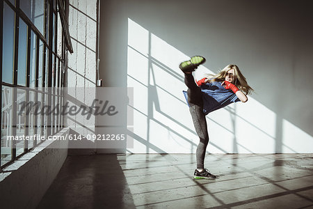 Full length front view of young woman in gym in kickboxing stance looking away