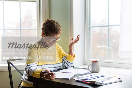 Happy senior woman writing at desk