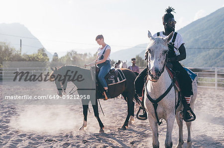 Young hipster man and woman riding horses in rural equestrian arena, Primaluna, Trentino-Alto Adige, Italy