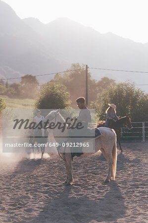 Young adults horse riding in rural equestrian arena, Primaluna, Trentino-Alto Adige, Italy