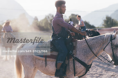 Young man and friends horse riding in rural equestrian arena, Primaluna, Trentino-Alto Adige, Italy