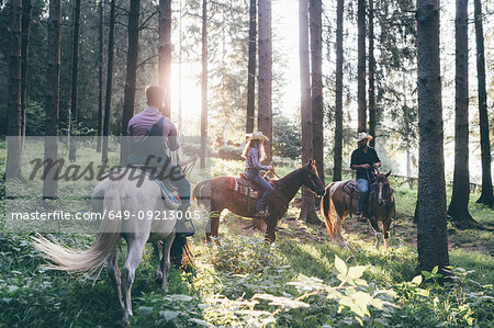 Young adults horse riding in sunlit forest, Primaluna, Trentino-Alto Adige, Italy