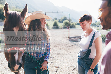 Young cowgirl with horse in rural equestrian arena