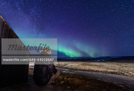 Man sitting in front of northern lights, Skogar, Iceland