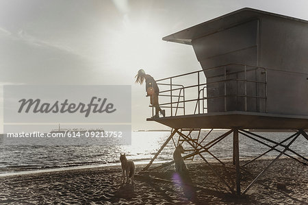 Woman on lifeguard tower, sunset in background