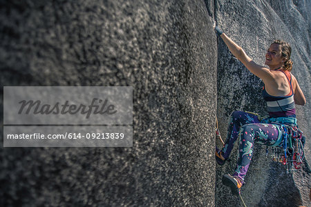 Young female climber climbing rock face, Smoke Bluffs, Squamish, British Columbia, Canada