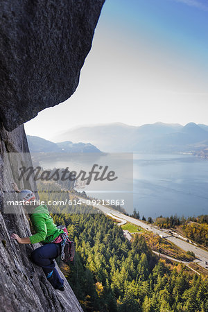 Young female rock climber climbing up rock face, elevated view, The Chief, Squamish, British Columbia, Canada
