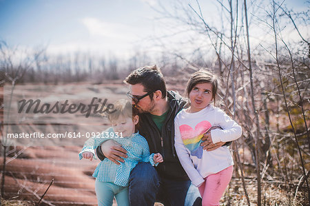 Female toddler with sister and father posing and pulling faces