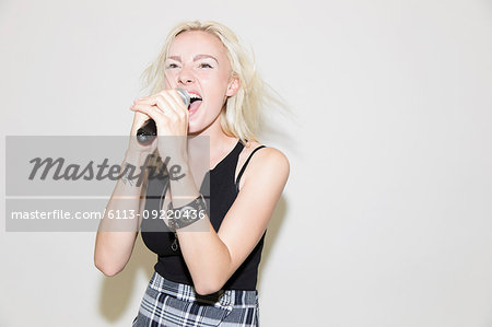Young woman singing into microphone