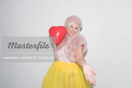 Portrait carefree, playful senior woman with heart-shape balloon