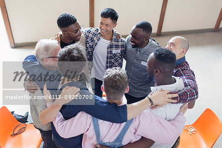 Men hugging in circle in group therapy