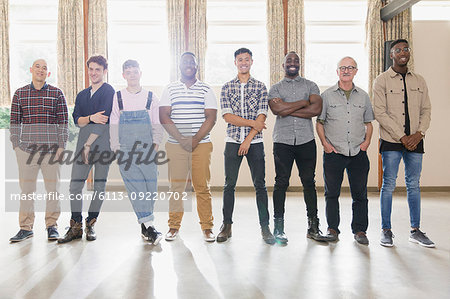 Portrait confident men standing in a row in community center