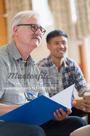 Attentive senior man taking notes in meeting
